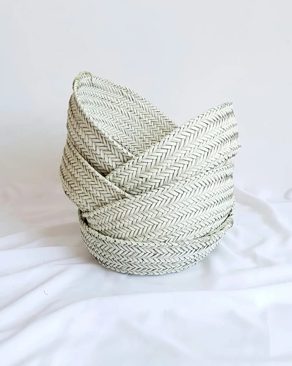 A round grey woven basket on white linen